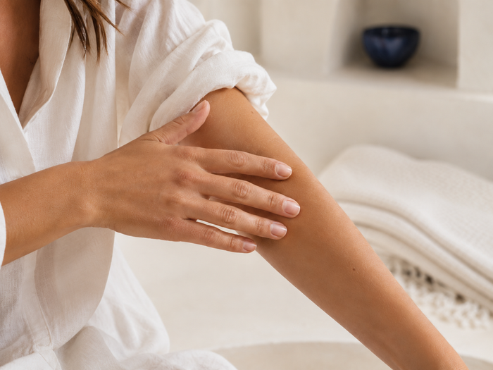 Femme exfoliant doucement la peau de son bras avec la main.